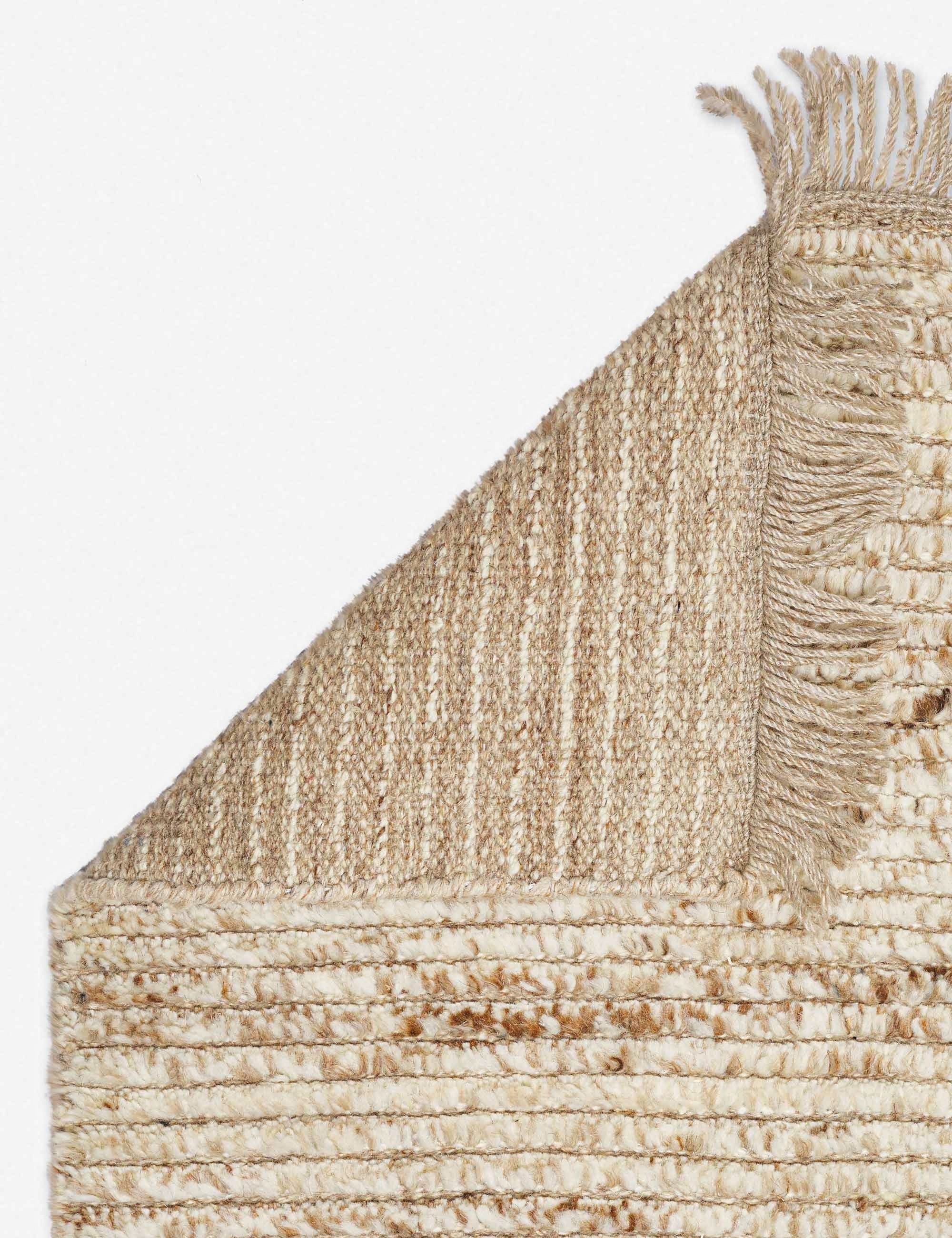 The corner of the Kenzi sand rug folded over itself
