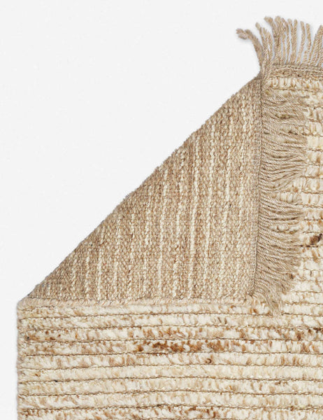 #size::6--x-9- #size::8--x-10- #size::9--x-12- #color::sand #size::10--x-14- | The corner of the Kenzi sand rug folded over itself