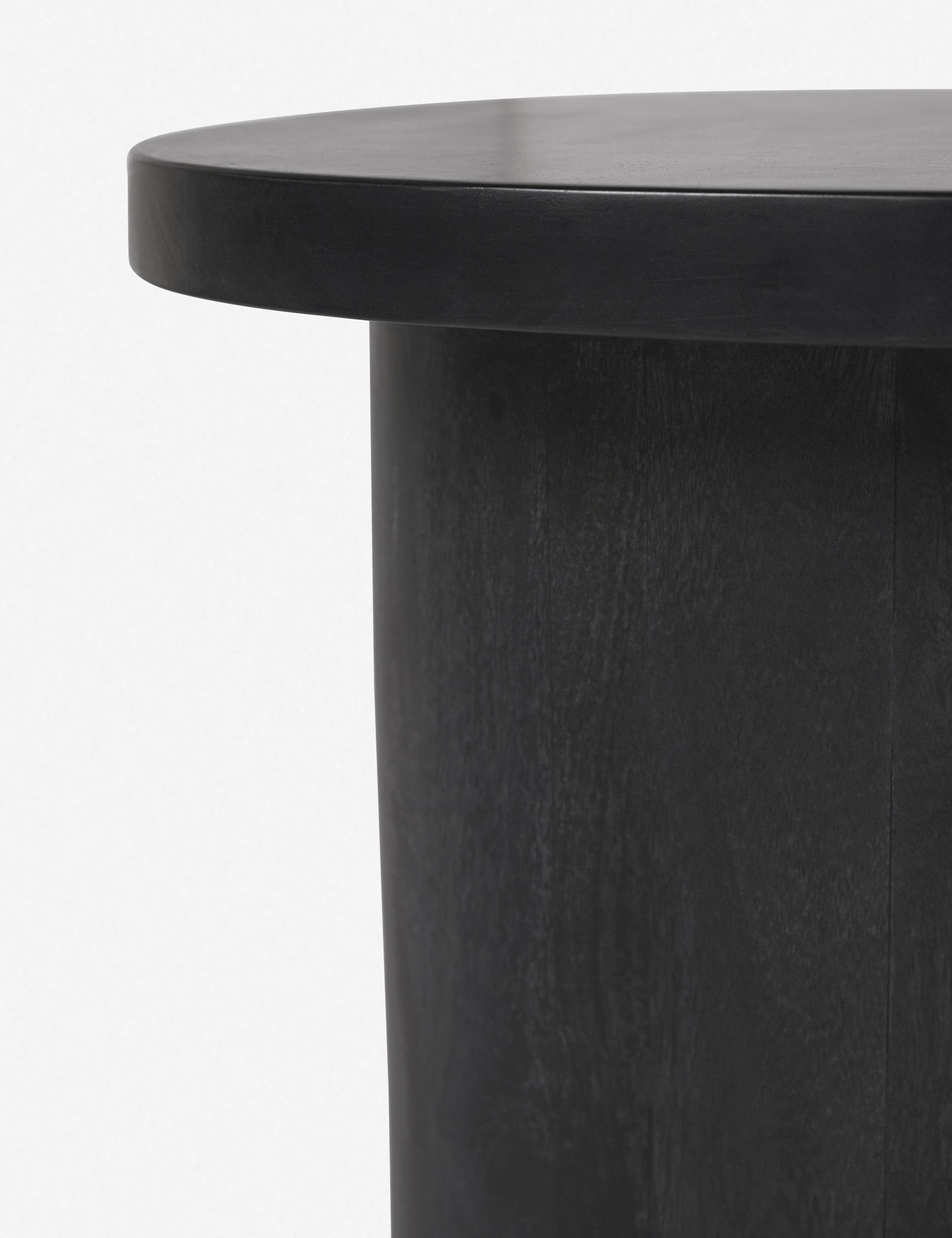 Close-up of the rim of the top of the Luna black wood round side table and the leg