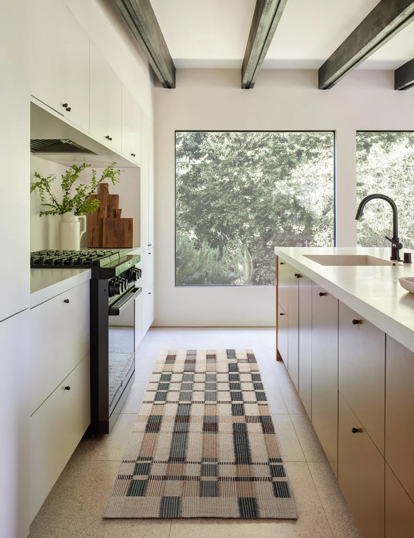 #size::2-6--x-8- | The marli rug in its runner size lays in a kitchen with white cabinetry, black beamed ceilings, and large square windows