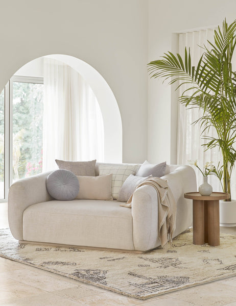 #color::ice-blue | The Monroe ice blue velvet round pillow sits on a white accent chair