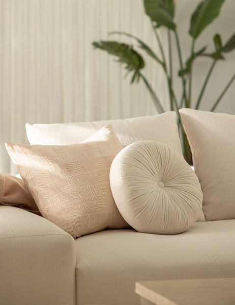 #color::oyster | The Monroe oyster white velvet round pillow sits on a white accent chair