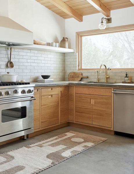 #size::2-6--x-8- | The Abode geometric two-toned kand-knotted floor rug by Élan Byrd with woven border in its runner size sits in a kitchen with wooden cabinetry and a gray subway-tile backsplash atop a concrete floor