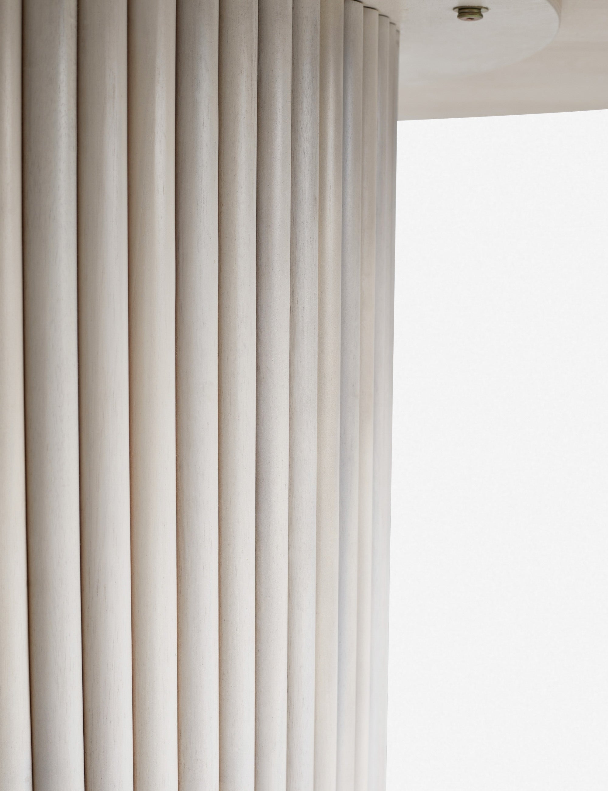 Close-up of the textured paneling of the white-washed acacia wood on the pedestal base of the Rutherford round dining table.