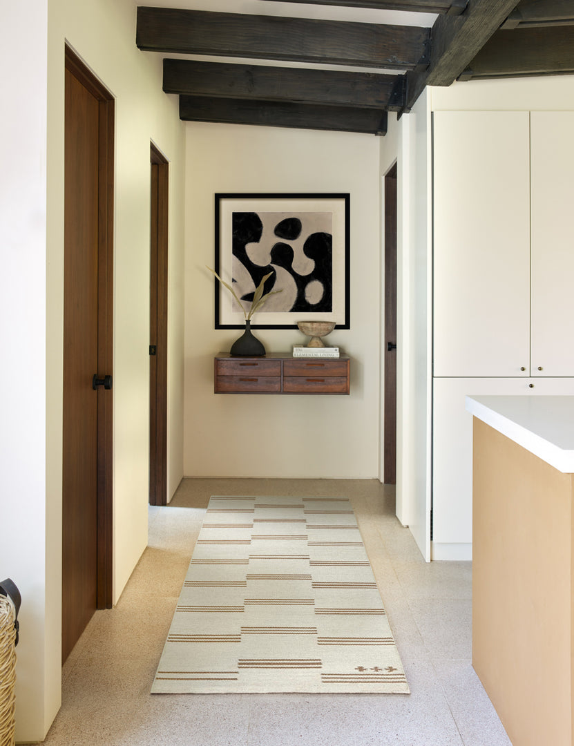 #size::2-6--x-8- | The Stripe break flatweave rug by Sarah Sherman Samuel in its runner size lays in a hallway with a wooden shelf, a black sculptural vase, and an abstract wall art